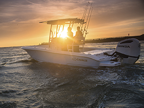 A boat using a Honda outboard on the water at sunset